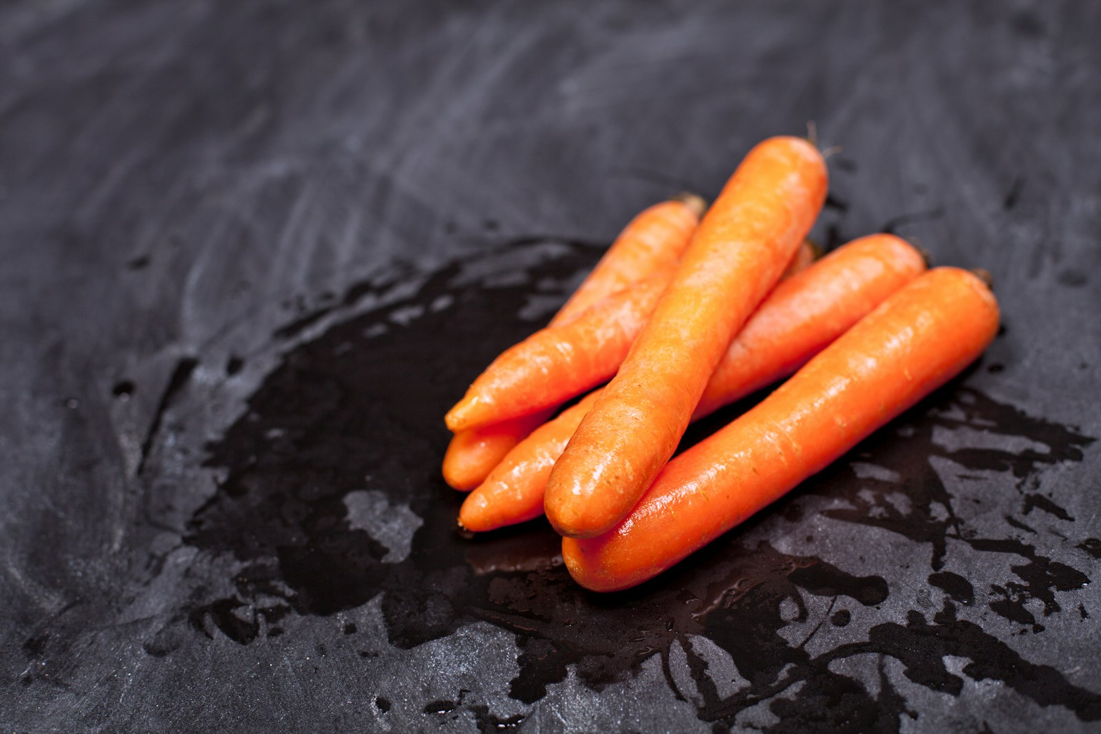 A pile of carrots sitting on top of a black surface
